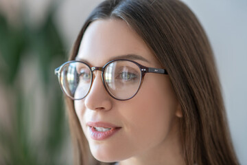 Headshot of long-haired woman in eyeglasses looking positive