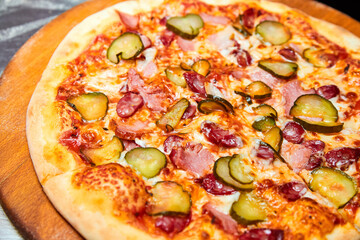 Fresh pizza pickles, bacon, sausages and cheese on a wooden board. Close-up, selective focus.
