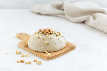 Homemade vegan cashew cheese with walnuts on a light table.