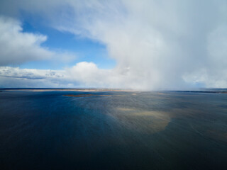 Dramatic sky with clouds above the blue lake or river before the rain.