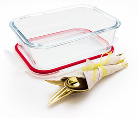 Empty and open glass tupperware with cutlery and napkin. Isolated on white background.