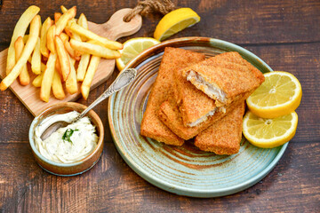  Fish and chips .Close up of   crispy breaded  deep fried fish fingers with breadcrumbs served with remoulade sauce and  lemon