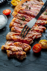 Red beef cutlet (cow, heifer, veal) cooked on the grill. Cut into strips. Top view. Fork pricking a piece of red beef cutlet (beef, heifer, veal) cooked on the grill.
