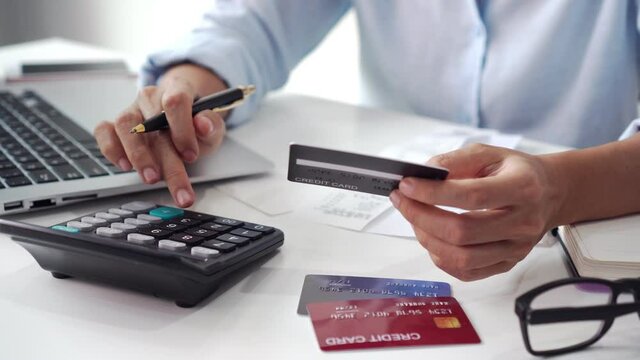 Asian businesswoman working at office. Female checking account balance and calculating credit card expenses. Family financial planning and business concept. Close up.