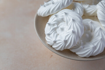 Plate with empty meringue nests, light stone background. Concept for a tasty sweet dessert.