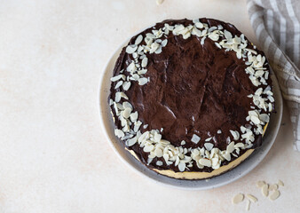 Delicious creamy cheesecake decorated with chocolate glaze and almond, light concrete background. No bake mousse dessert. Top view.
