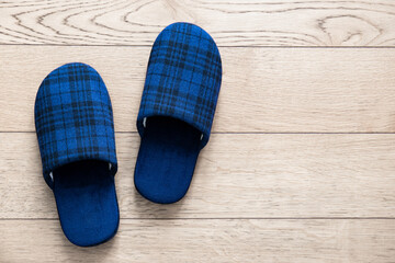 Blue slippers on parquet floor. Picture taken at home representing a pair of tartan fabric slippers abandoned on the floor.