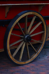 Wheel from cart, stroller. Antique trolley wheel made of wood and iron lining, Wheel from a modern red carriage.
