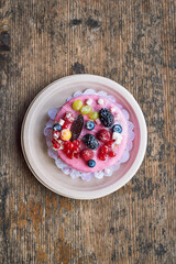 Sweet cheese cake with fresh berries and yoghurt cream. Delicious raspberry cake with fresh strawberries, raspberries, blueberry, currants and blackberry fruits on wooden background with copy space.
