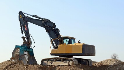 Excavator with a large screening bucket on a gravel ground. © luca piccini basile
