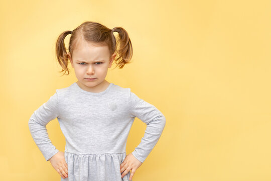 Angry cute child girl showing frustration and disagreemen over pastel yellow isolated background. Negative human emotions facial expressions feelings. Banner, place for text, mockup