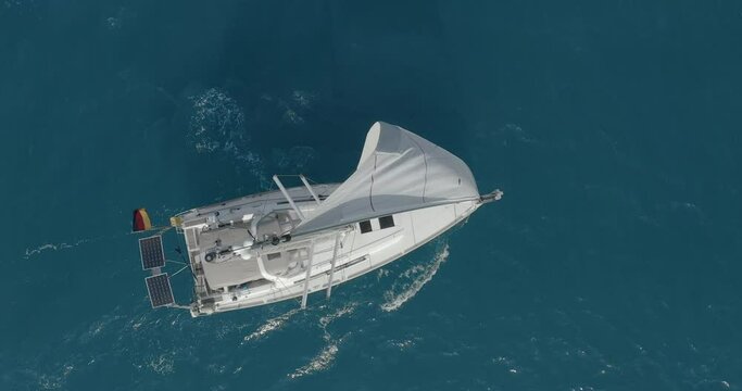 Yacht with reflection sailing on open sea aerial. Nobody nature seascape with sail boat cruising at ocean bay. Mountain landscape of Arran Island, Scotland. Cinematic summer vacation scenery.