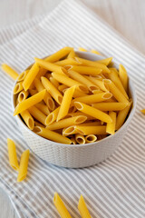 Uncooked Organic Penne Pasta in a Bowl, low angle view.