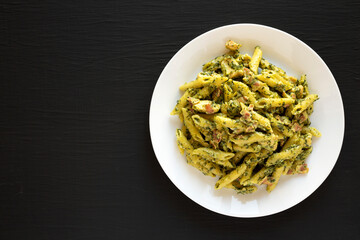 Homemade One-Pot Chicken Spinach Bacon Alfredo Pasta on a plate on a black background, top view. Space for text.
