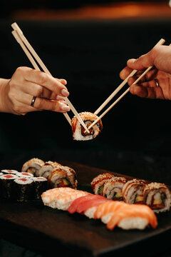 Man and woman pick up sushi with chopsticks at the same time