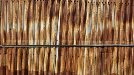 Rusty galvanized fence background. Old red-brown decayed galvanized wall vertical for background work. Selective focus