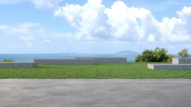 Gray concrete bench on green grass garden in modern city park. Road 3d rendering with beach and sea view.