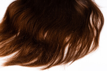 Curls of dark brown hair lie on a white background