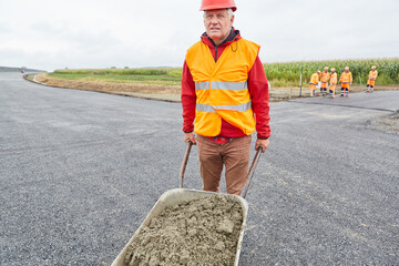 Construction worker pushes concrete in a wheelbarrow