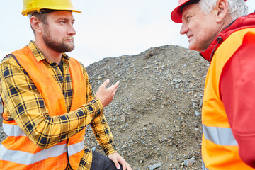 Construction worker and architect in front of mound on construction site