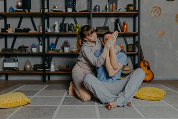 Couple doing Yoga at home in pajamas near bookshelf. Young man and woman doing sports at home.