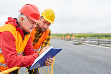Two construction workers as road builders with a checklist