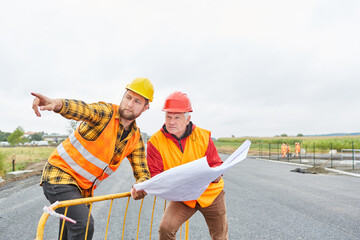 Architect and construction worker with floor plan for house building