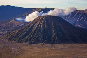 Fototapeta premium Mount Batok on the foreground and ash of the erupting and active Bromo volcano on the background. Bromo Tengger Semeru National Park, East Java, Indonesia.