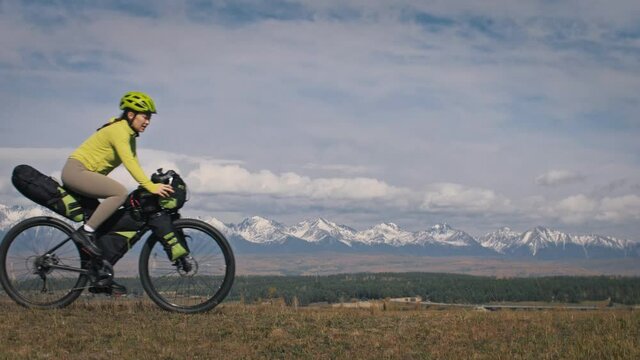 The man and woman travel on mixed terrain cycle touring with bikepacking. The love couple journey with tent in with bicycle bags. Stylish sportswear.