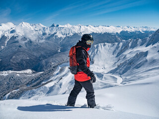 Man with snowboard at mountains background in ski resort of Krasnaya Polyana
