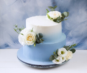 Two tiered modern  blue wedding cake with white roses and eucalyptus