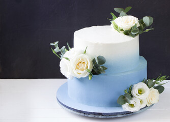 Two tiered modern  blue wedding cake with white roses and eucalyptus