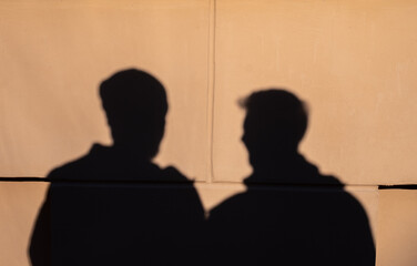 Two male shadows against the wall. They're discussing something.