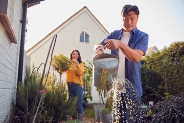 Mature Asian Couple At Work Watering And Caring For Plants In Garden At Home © Monkey Business