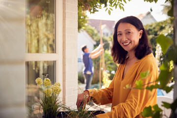 Portrait Of Mature Asian Woman Planting Plants Into Wooden Garden Planter At Home