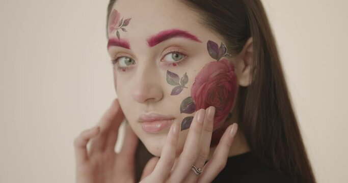 portrait of a young beautiful girl with long dark hair with a chic body art on her face