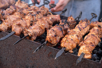 A man cooks meat on coals.