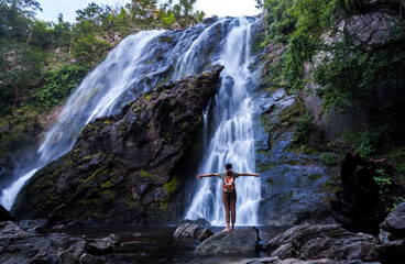 Blurry light of backpack girl standing and motion blurred water of on Khlong Lan Waterfall, Beautiful waterfalls in klong Lan national park of Thailand. Khlong Lan Waterfall, KamphaengPhet Province
