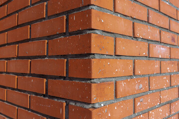 Red brick wall corner texture with dots and traces of white paint on it