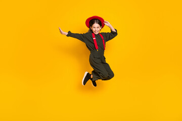 Fototapeta na wymiar Full length body size photo of jumping girl happy wearing red headwear laughing isolated vivid yellow color background