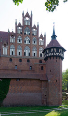Medieval castle surrounded by beautiful gardens and greenery. Old brick castle in Poland. Traditional architecture. Summer landscape
