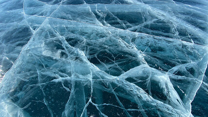 Unique pattern of frozen Lake Baikal. Blue transparent clear smooth ice with deep cracks. View from...