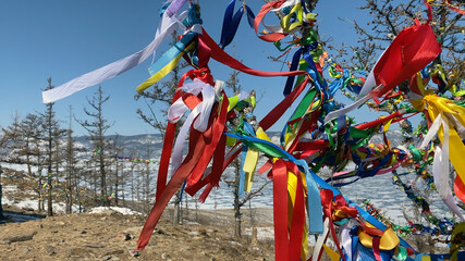 Colorful Tibetan Buddhist ribbons tied to a tree flutter in the wind. Olkhon Island.
