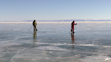 A guy and a girl are skating on the ice of the frozen Lake Baikal. A beautiful winter landscape
