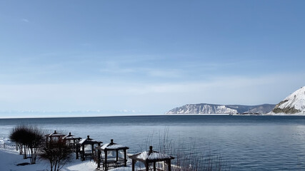 Fototapeta na wymiar The non-freezing Angara River flows into the icy Lake Baikal. Northern landscape of frozen Lake Baikal