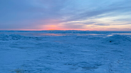 Amazing sunrise on the northern frosty Lake Baikal. Panorama of the northern landscape of the frozen lake.