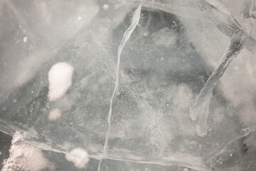 Amazing chunks of ice in the skylight. Transparent ice with cracks covered with snow. Winter natural background. Hummocks of frozen Lake Baikal.