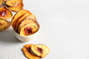 Dried sliced fruits peach chips in bowl on white background with copy space. Close up. Snack vegan sugarfree food.