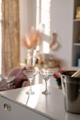 Two elegant champagne glasses in the shape of a bowl in a beautiful feminine interior. Meeting of two girlfriends concept. Preparing for a date. Female friendship. Martini. St. Valentine's Day
