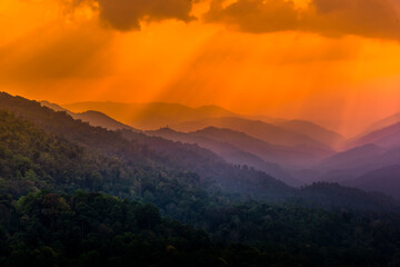 Tropical forest with mountains and majestic orange sky and clouds. Camping site at Maewong National Park, Nakhonsawan, Thailand.